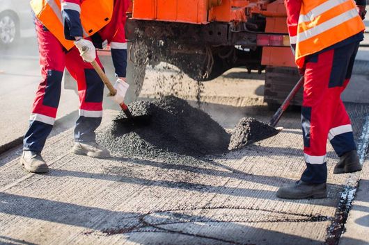 Työmiehet levittävät tielle uutta asfalttia